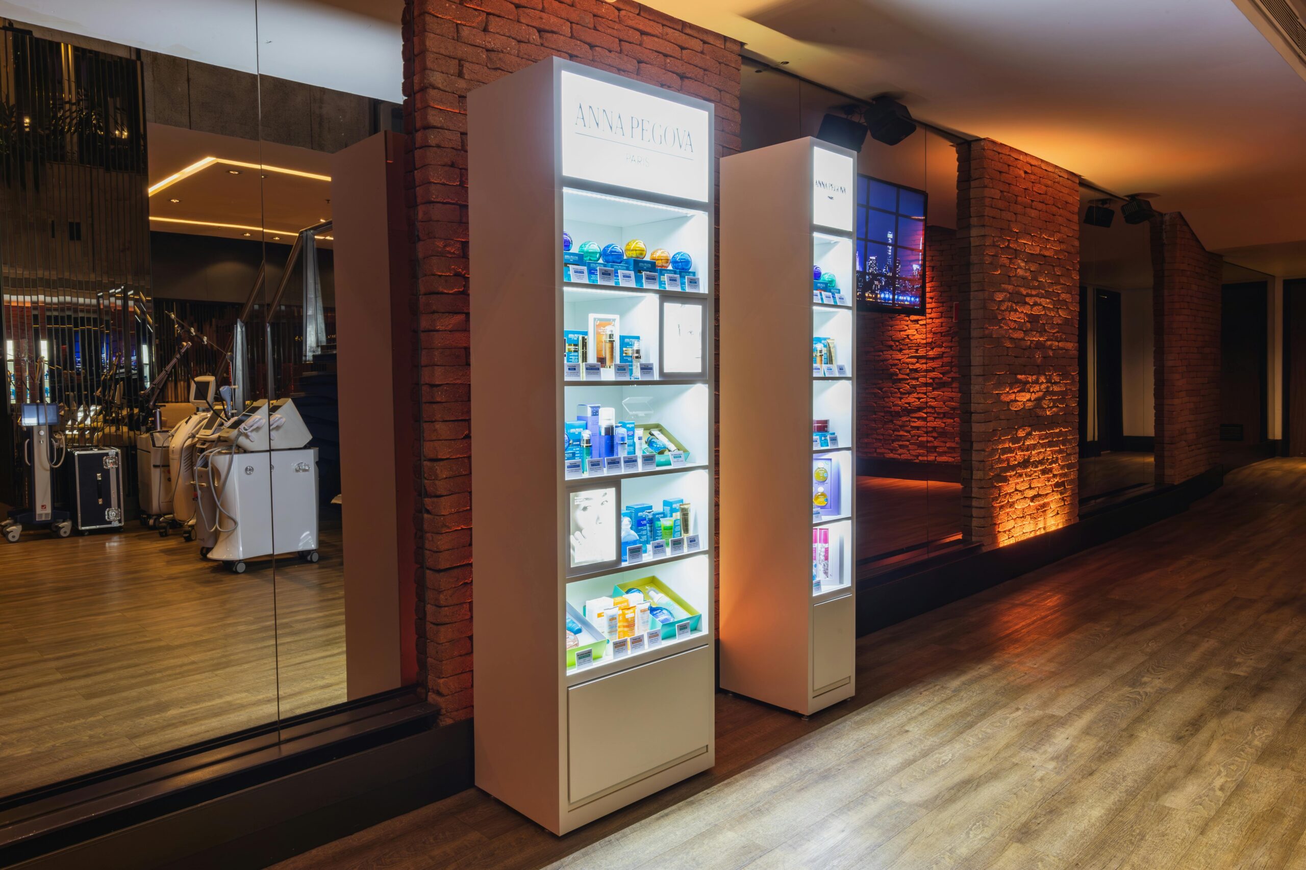Illuminated cosmetic display shelves in a stylish spa with brick accents and ambient lighting.